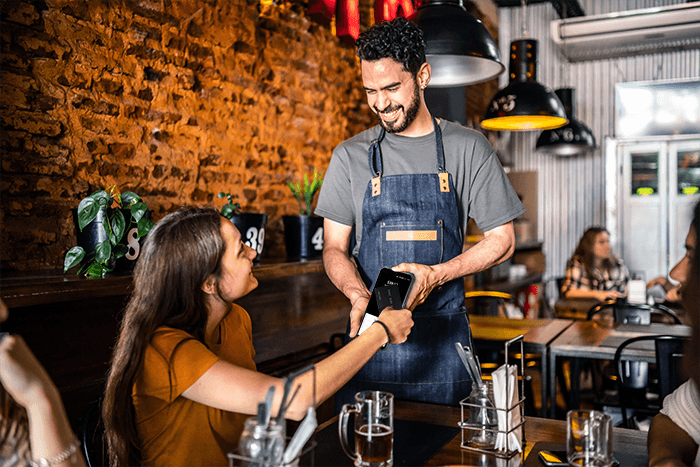 Bartender using a Shift4 Dine handheld at the bar